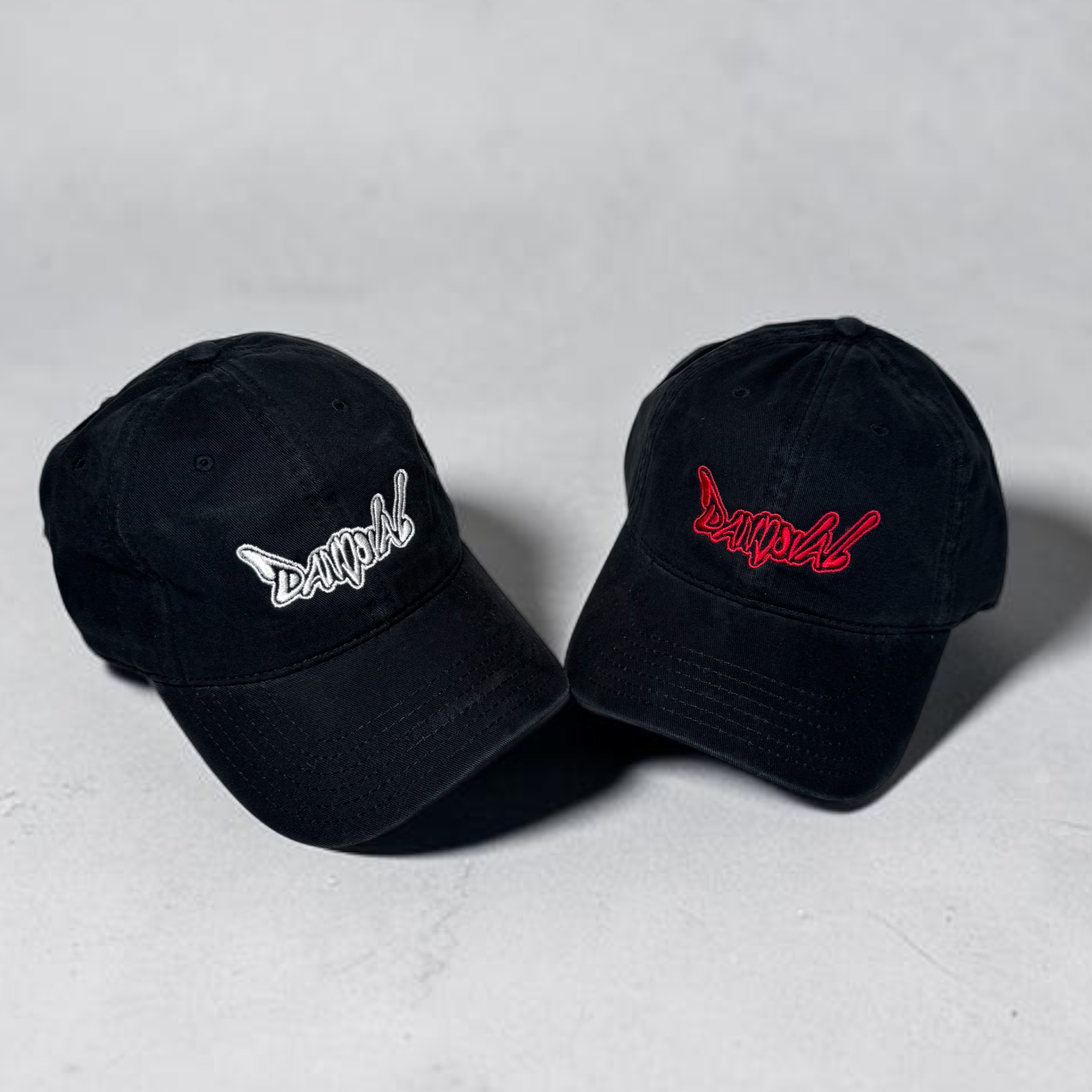 Two black baseball caps with embroidered logos on a light gray background