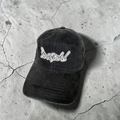 Black cap with white logo on a cracked concrete surface