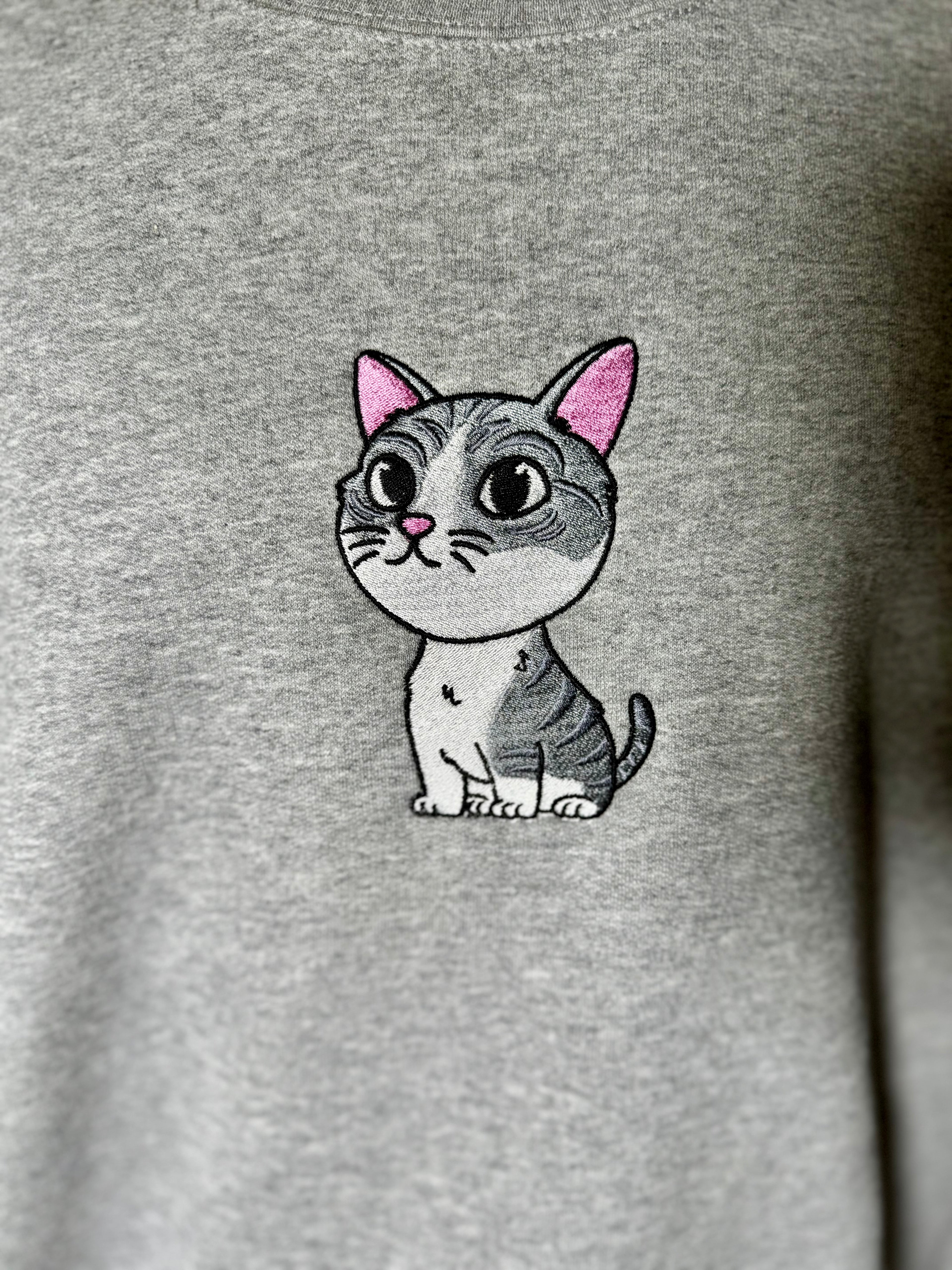 Embroidered cat design on a gray sweatshirt