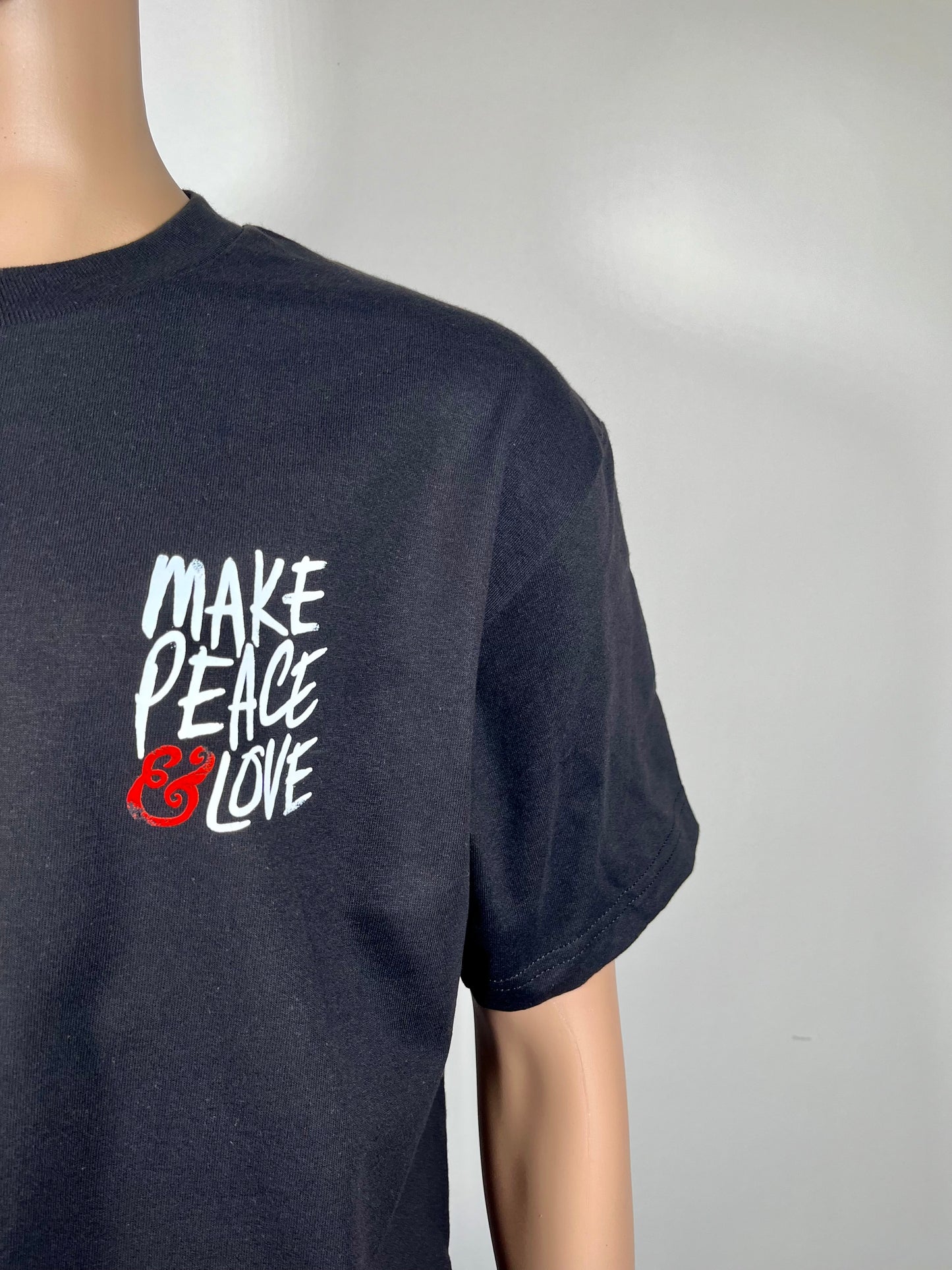 "MAKE PEACE & LOVE T-Shirt with white and red left print, made from 100% preshrunk cotton. Unisex design, showcasing a message of peace and love."