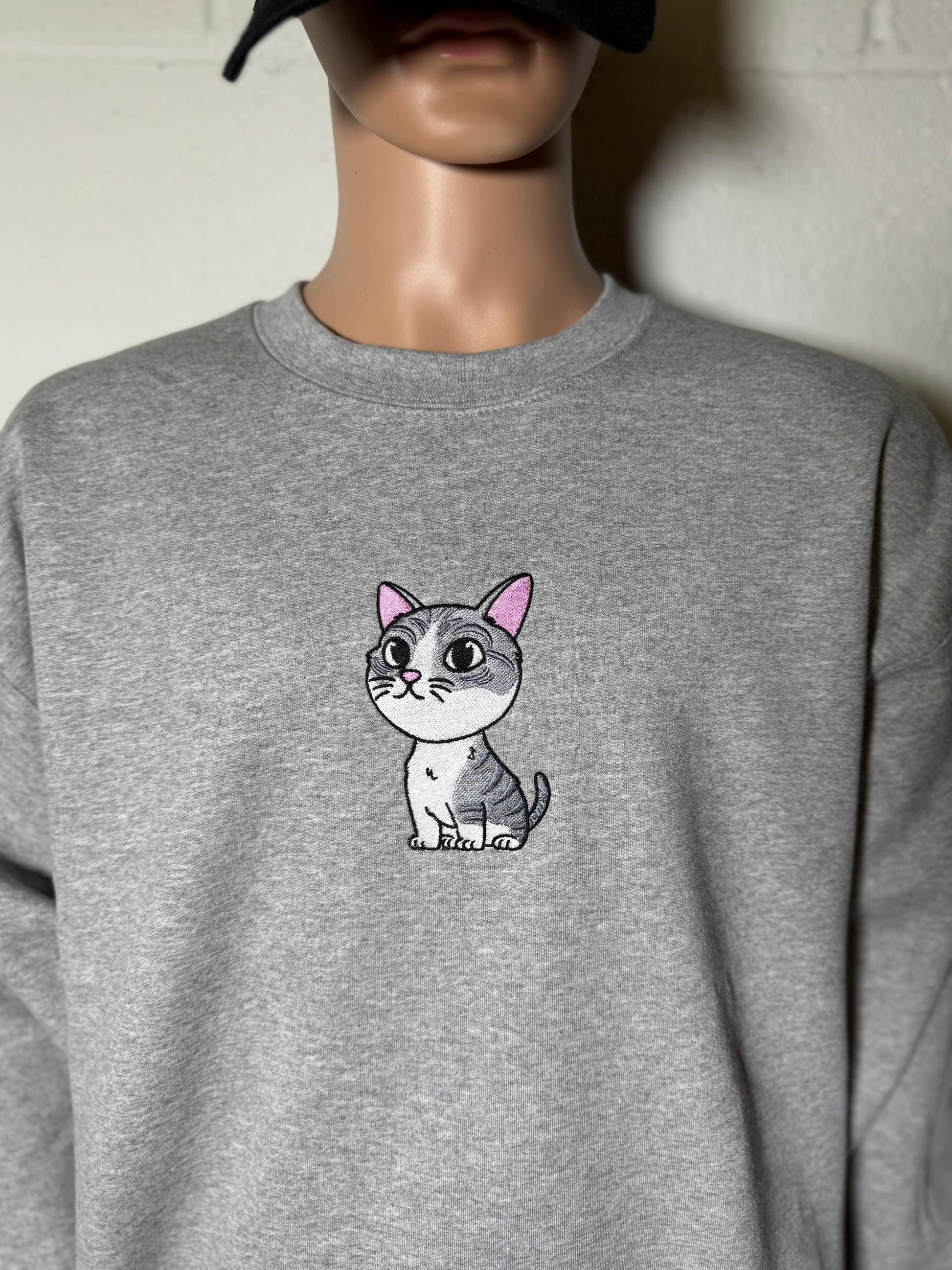 Gray sweatshirt with a small cat illustration on the chest against a neutral background