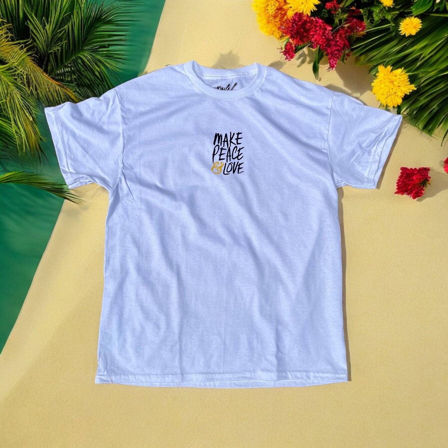 White t-shirt with 'Make Peace Love' text on a yellow surface with flowers and leaves.