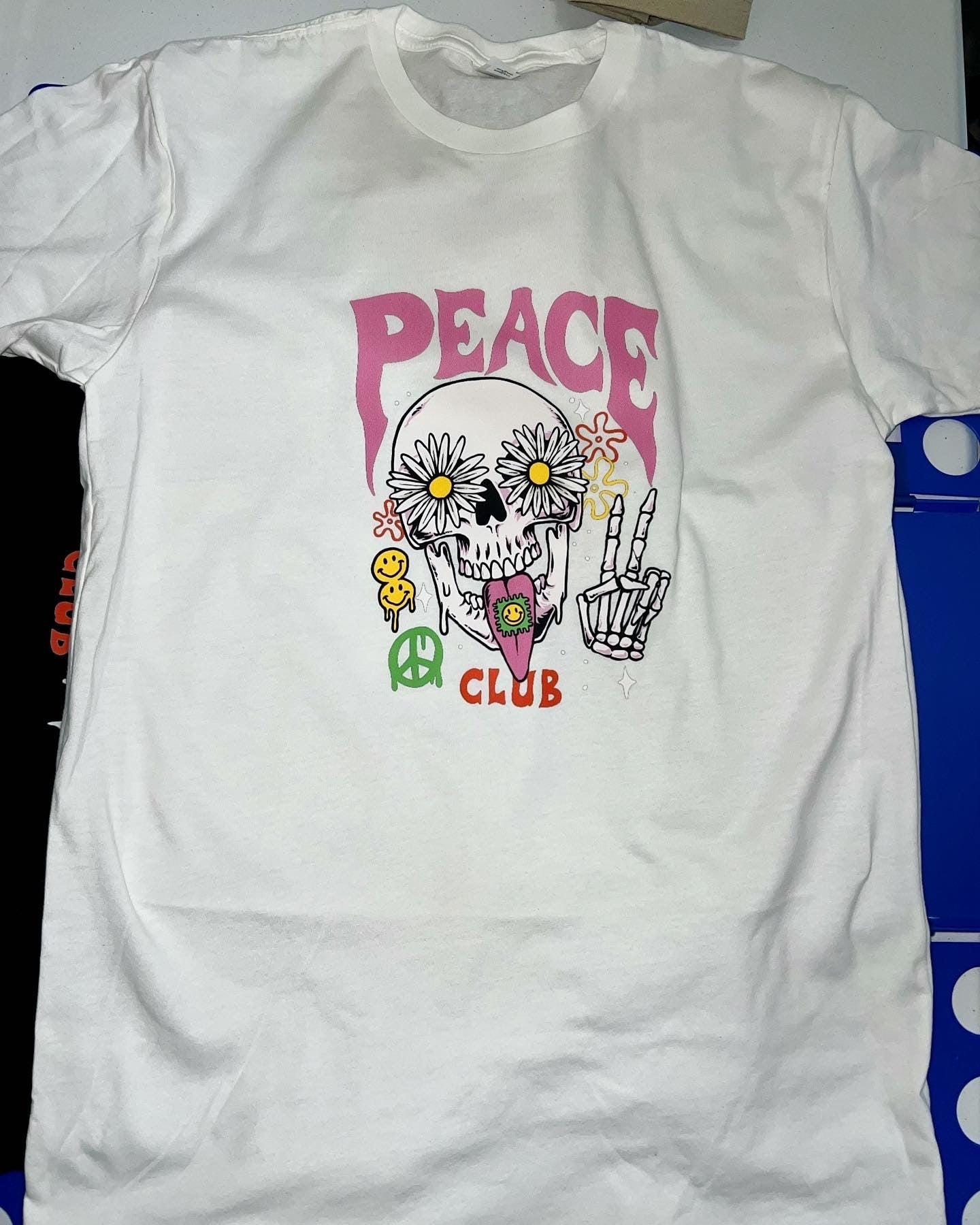 White t-shirt with a colorful skull design and 'Peace Club' text on a white background.