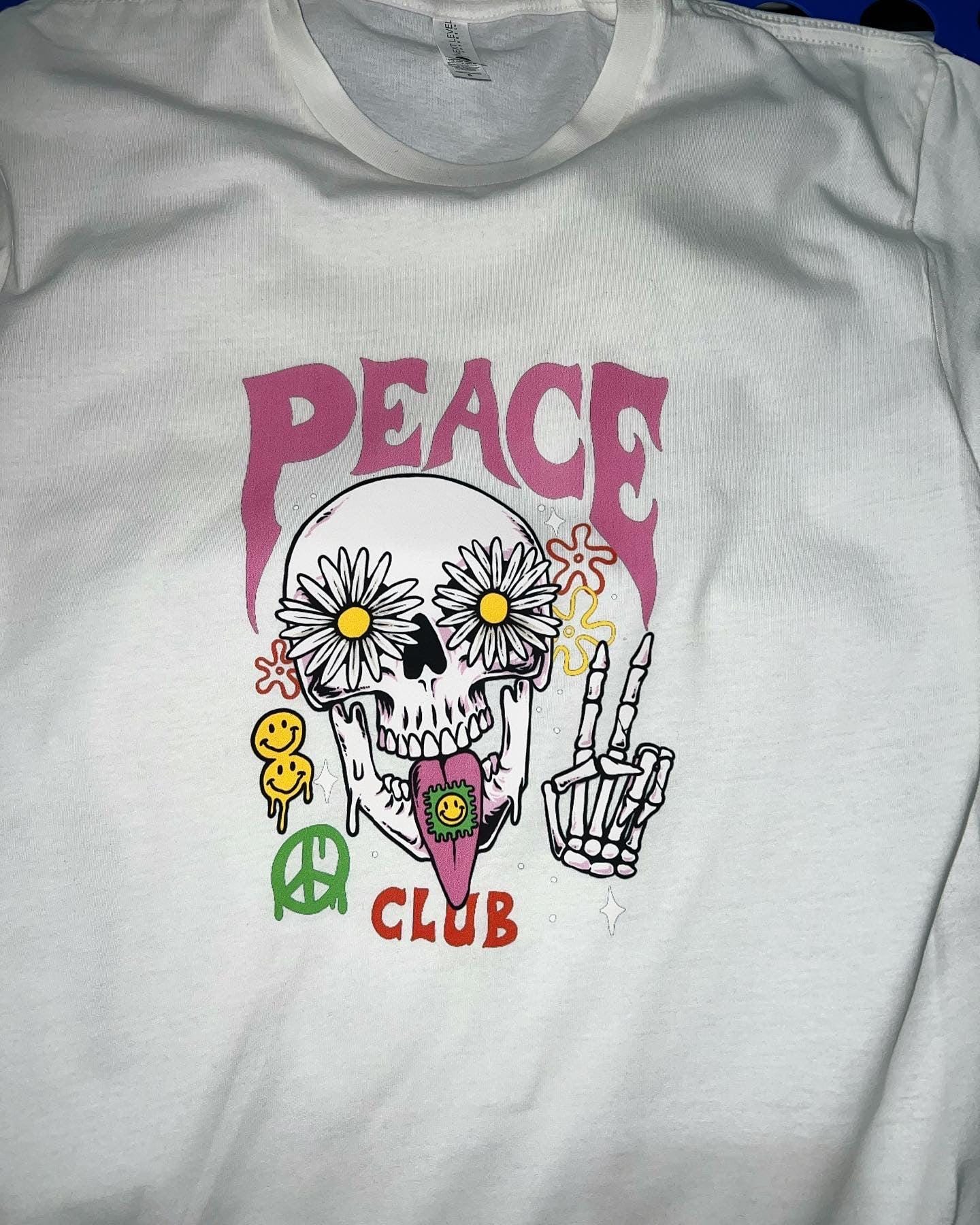 White sweatshirt with a colorful graphic design featuring a skeleton, flowers, and 'PEACE CLUB' text.