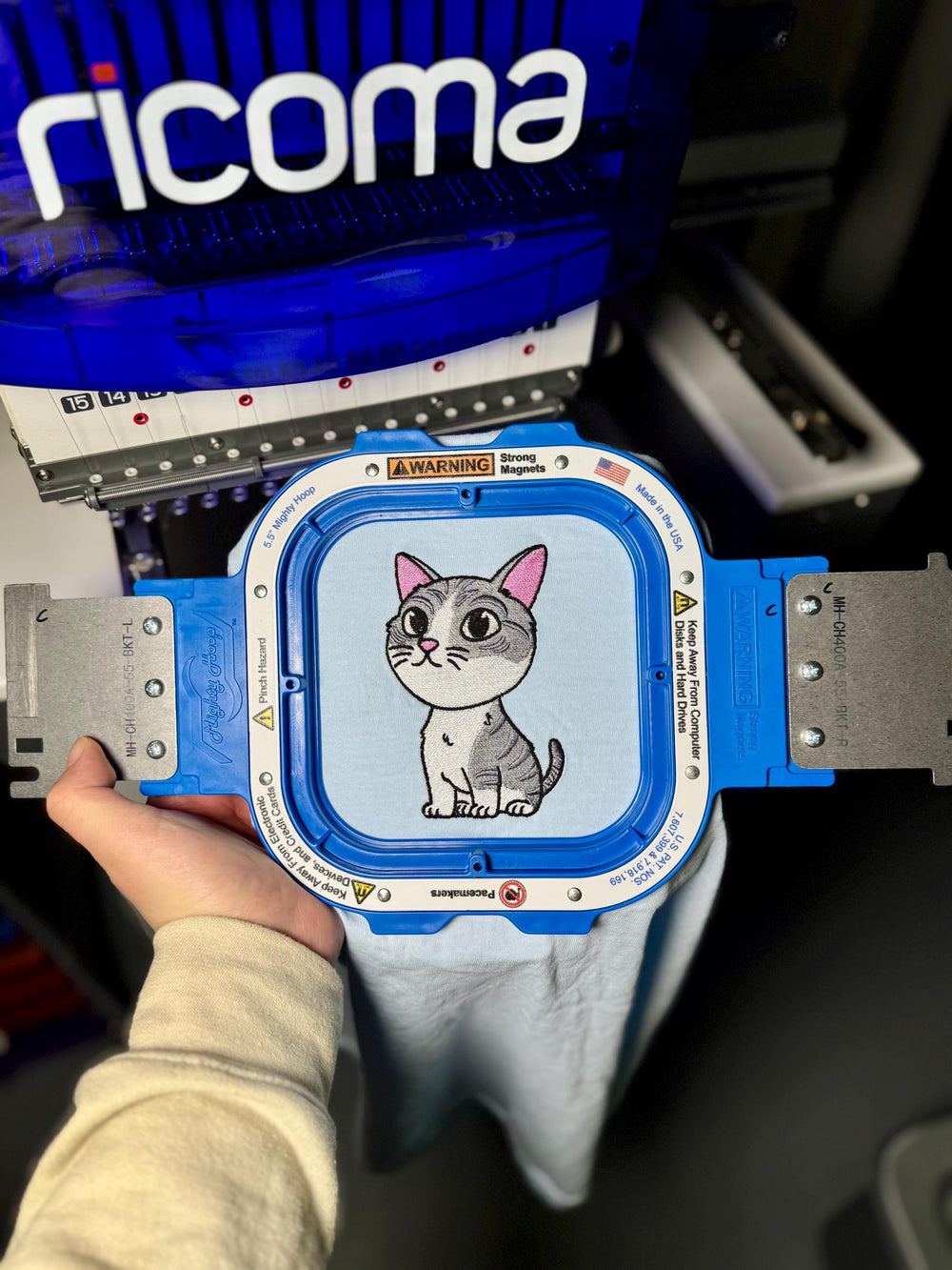 Blue measuring device with a cartoon cat on the screen, held by a person.