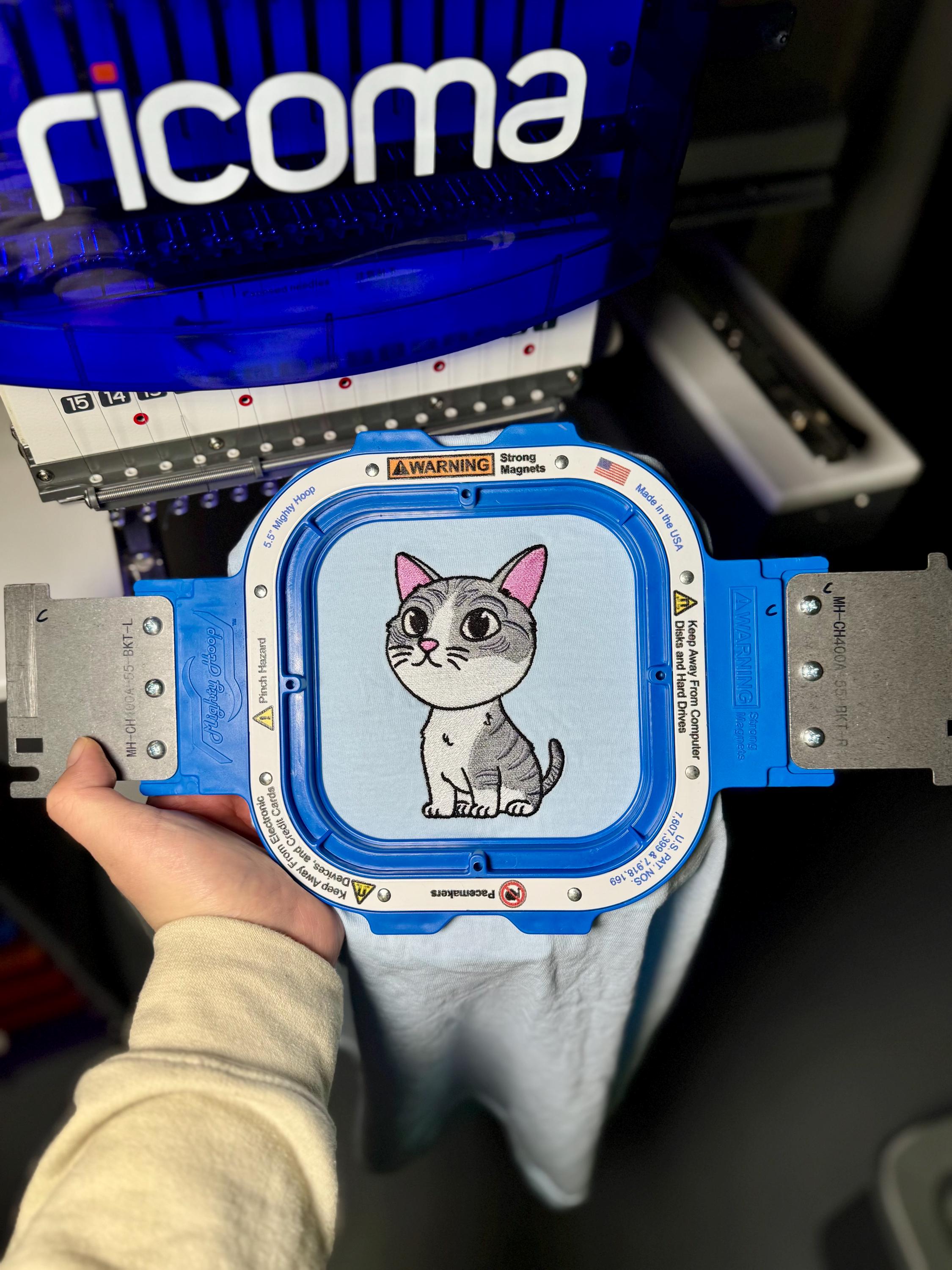 Blue measuring device with a cartoon cat on the screen, held by a person.
