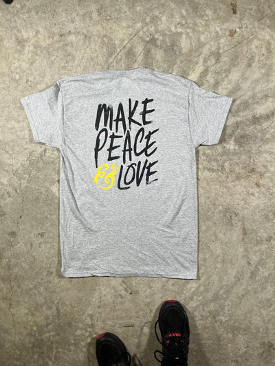 Gray t-shirt with 'MAKE PEACE LOVE' text on a concrete floor.