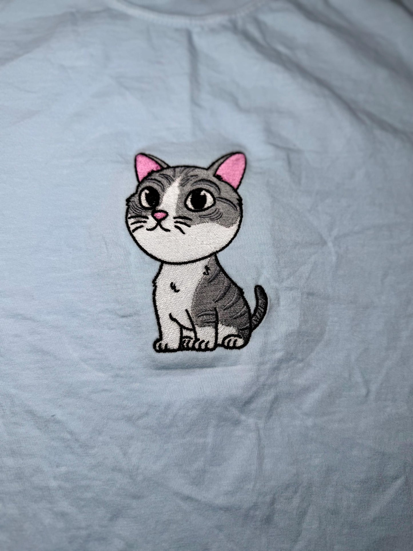 Embroidered cat patch on a light gray fabric background