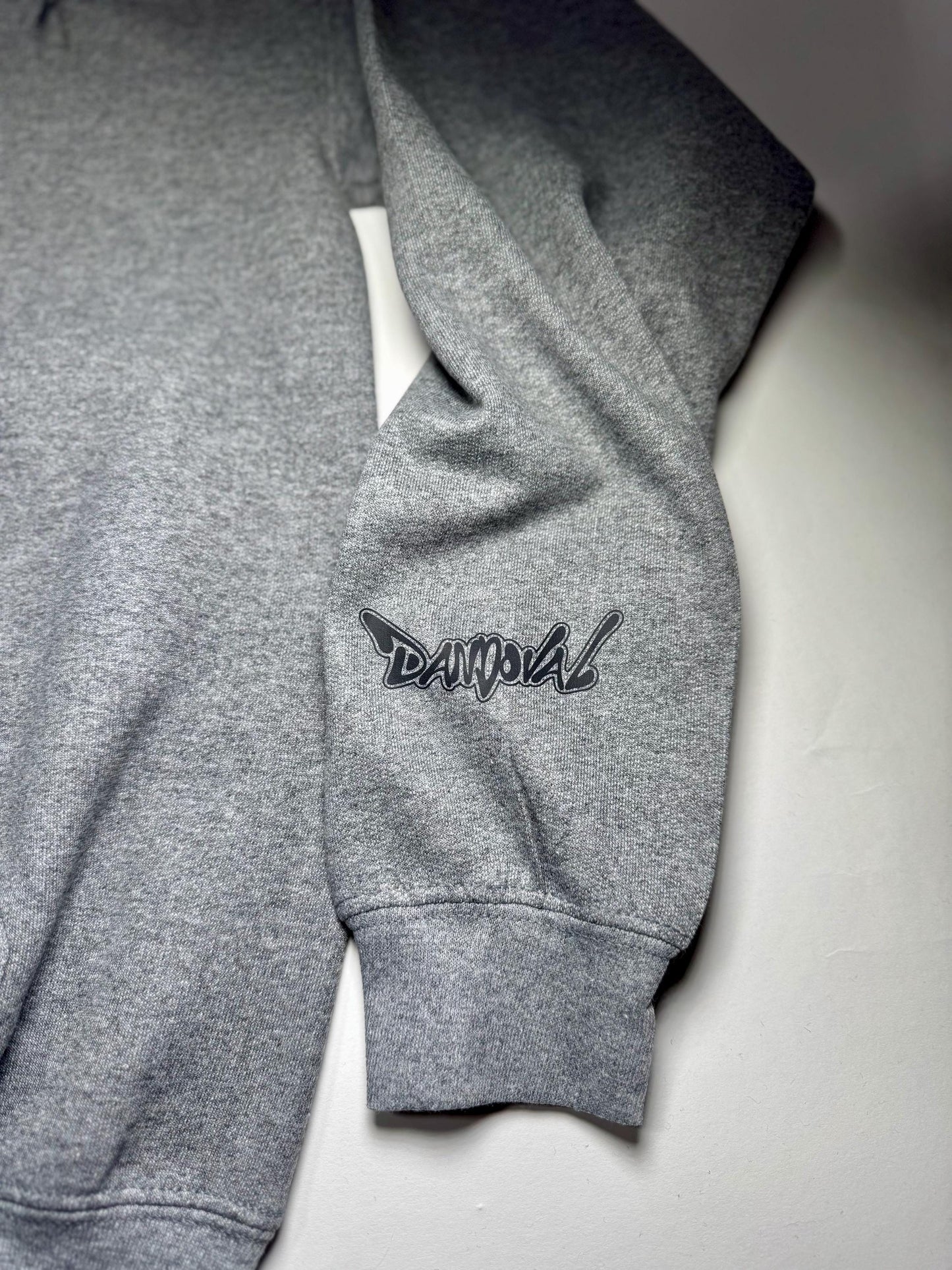 Gray sweatshirt with a logo on the sleeve against a light gray background