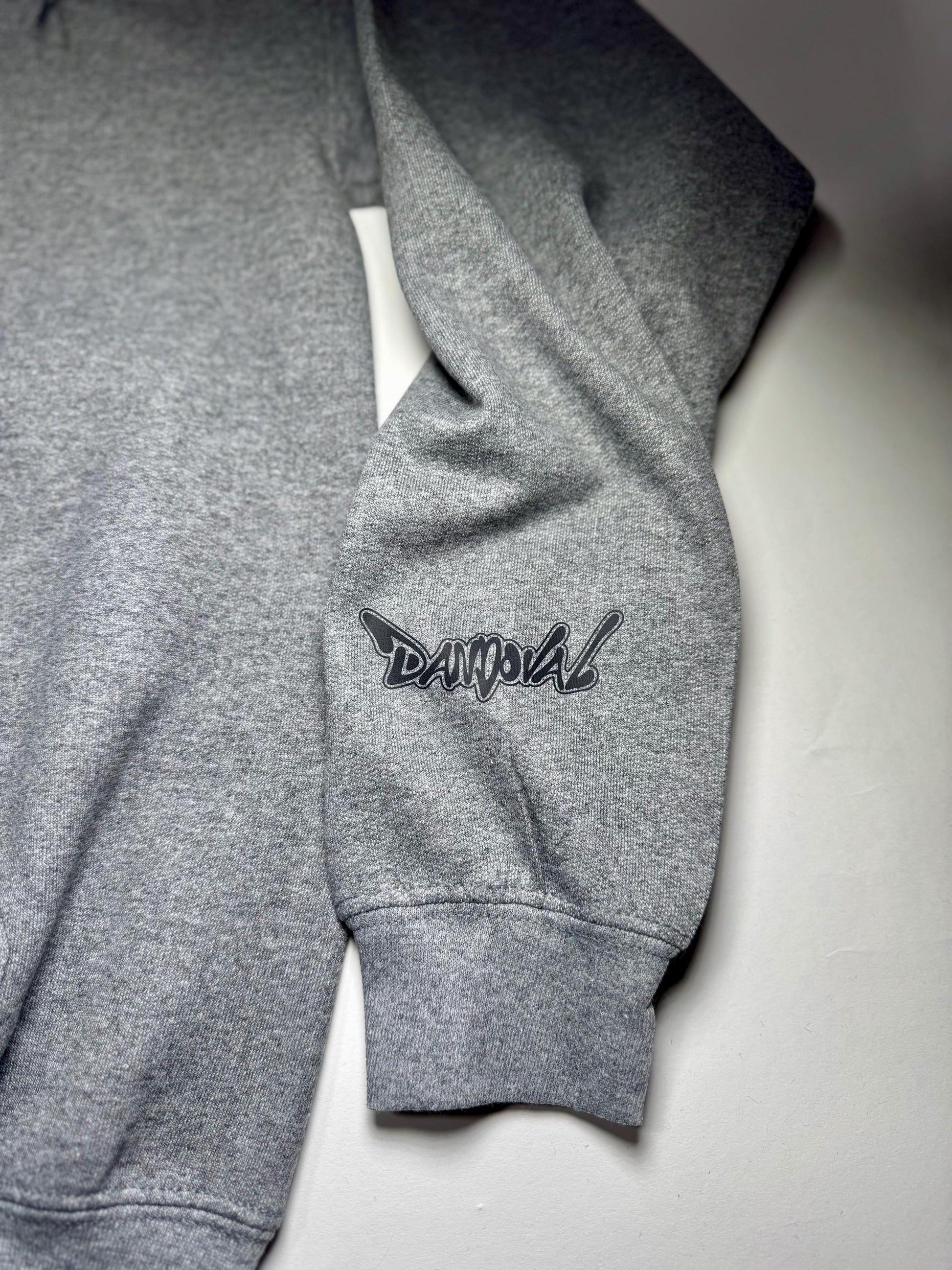 Gray sweatshirt with a logo on the sleeve against a light gray background